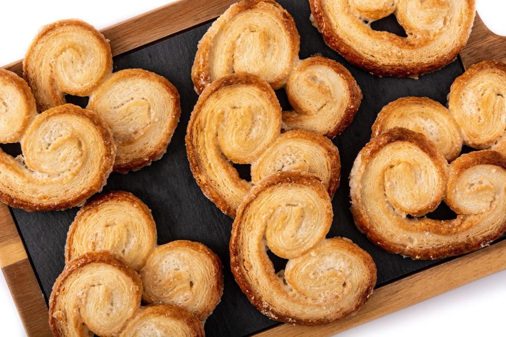 Golden-brown palmiers arranged on a wooden serving board
